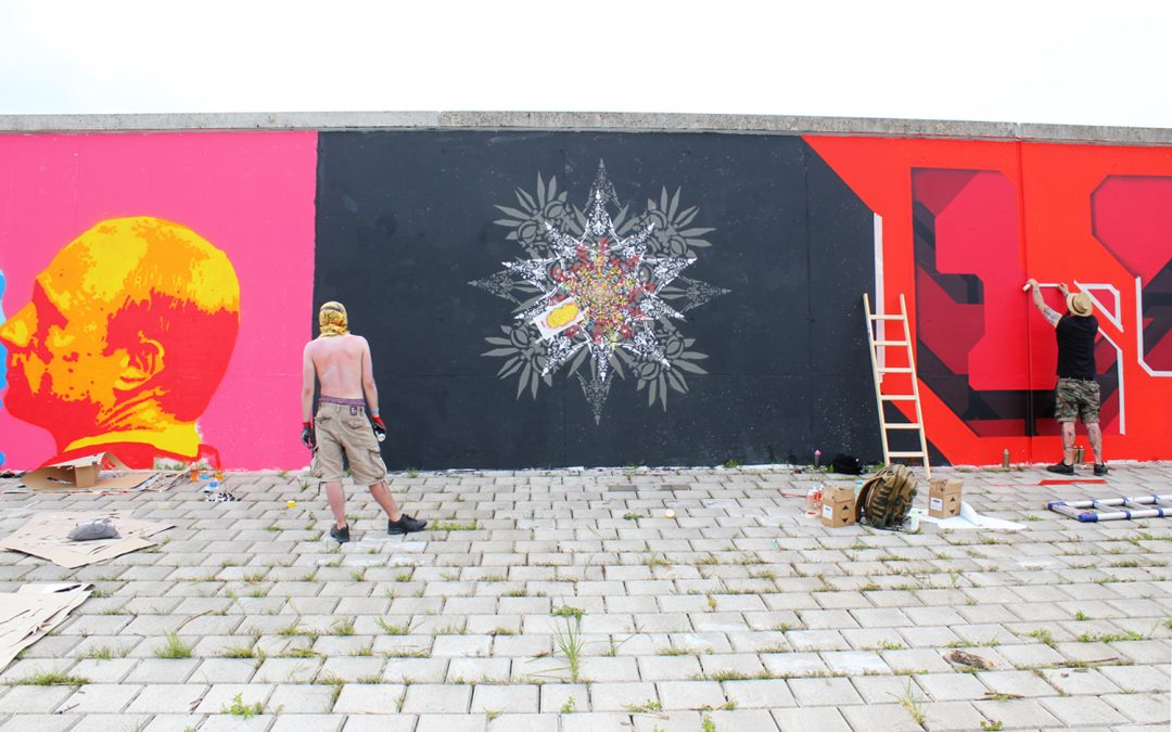 ErwaOne vor seinem Wandbild Streetart Urban Art Farbflut Festival 2018 Deichmauer