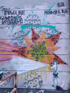 Kunstwerk von ErwaOne Streetart in Nürnberg, Figur Graffiti Entferner entfernt farbenfrohes muster eines Schablonenmotivs. Kulturoasis Nürnberg Zwischenstandnutzung AEG Gelände