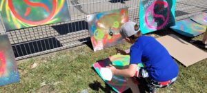 Ein kleiner Junge sprüht auf einen Karton während eines Tag der offenen Tür mit Streetart-Station durch Künstler Erwa.One
