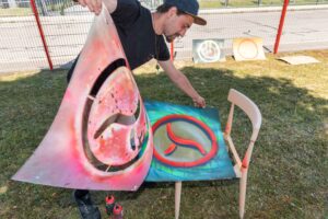 StreetartKünstler Erwa.One während eines B2B Firmenevents mit einer Streetart Station, 2022. Absetzen der Schablone vom besprühten Karton.