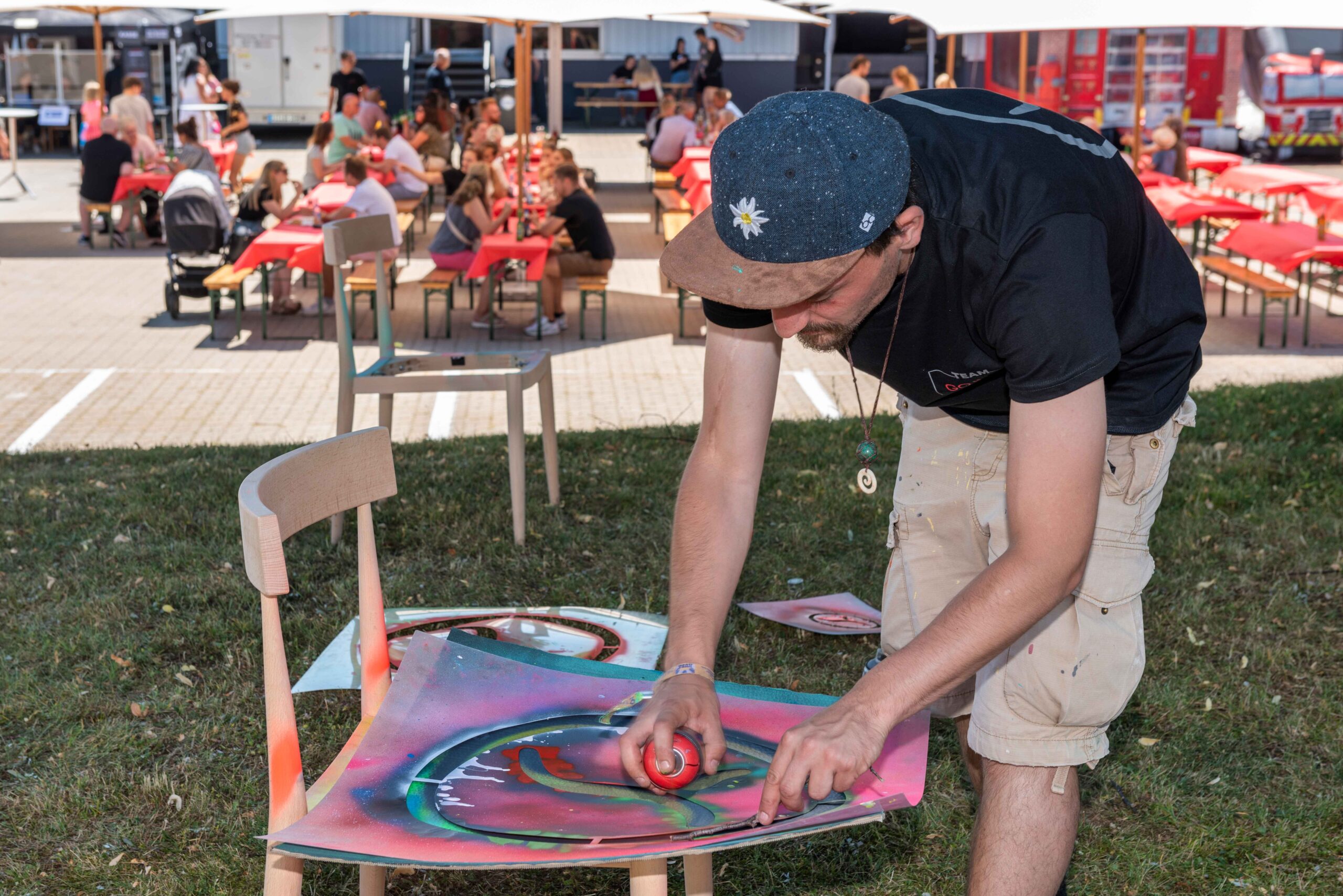 StreetartKünstler Erwa.One während eines B2B Firmenevents mit einer Streetart Station, 2022. Künstler besprüht einen Karton mit einer Schablone des Unternehmenslogos