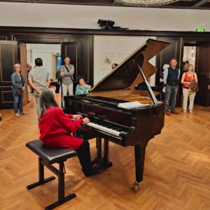 Frau spielt Klavier während Ausstellungseröffnung Bildende Kunst München Seerosenkreis