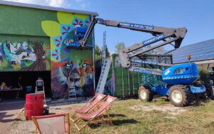 Bavarian Safari Graffiti Jam Landsberg 2023 Hebebühne im Einsatz, Singe Mandala in Arbeit, Liegestühle vor der Wand für Besucher