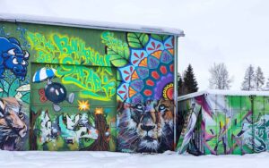 Bavarian Safari Graffiti Jam Landsberg 2023 Aussenfassade der Gewerbehalle im Winter unter einer Schneedecke. Die Streetart und Graffiti Werke leuchten farbenfroh