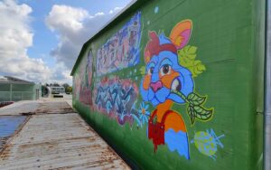Bavarian Safari Graffiti Jam Landsberg 2023 Zweite Hauptwand Seitenfoto mit blauem Streetart Hasen im Vordergrund und Graffiti im Hintergrund, links Container, hinten Rational Gelände