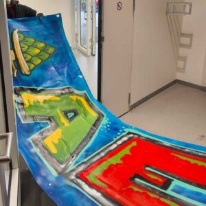 Graffiti-Sprühworkshop in der Handwerkskammer Schwaben mit den Nachwuchsspielern der Augsburger Panther und des FCA. Das fertige AEV-Graffiti wird in den Trockenraum getragen. Augsburger Eislaufverein / Augsburger Panther