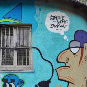 "Words for Democracy"-Projekt mit Trafo-Haus Gestaltung durch die Workshop-Teilnehmer in der Riederau am Ammersee. Bjarne Jaschhof Kunstwerk Charakter mit Sprechblase Streetwork DIessen dem Logo der Ammerseewerke und einem blauen Hintergrund. Streetart Werk öffentlicher Raum.