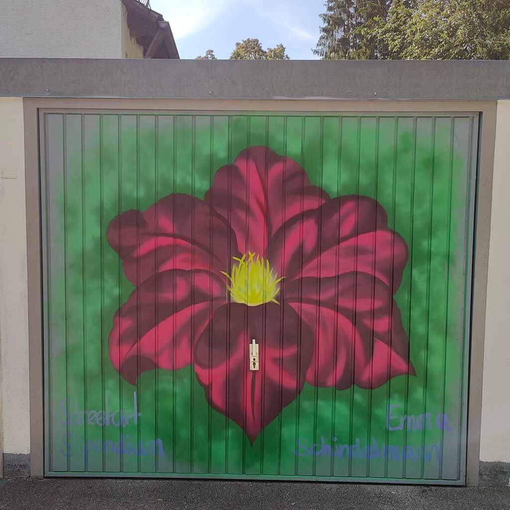U27 Streetart Stipendium Landsberg 2024: Kunstwerk einer roten Blume auf dem Tor einer Garage in Landsberg durch Stipendiatin Emma