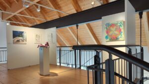 KULT Kunst Krumbach 2024 Kunstausstellung im mittelschwäbischen Heimatmuseum in Krumbach Schwaben, Blick auf die Ausstellung mit einem Kunstwerk von ErwaOne,modernes Museum mit Holzdecke und Stahlträgern, angenhemes Ambiente