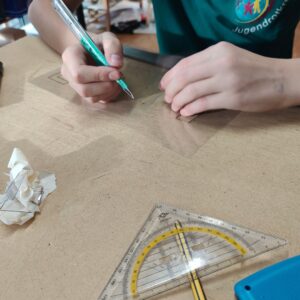 Sprüh-Workshop Urbane Kunst Methodik von ErwaOne an der Montessori-Schule von Kaufering. Ein Junge schneidet eine Schablone