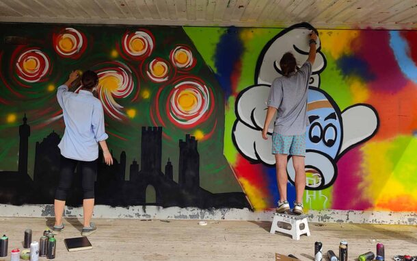 U27 Streetart Stipendium Landsberg am Lech Rückblick 2024: beide Stipendiaten Emma und Bjarne gestalten eine Containerfläche am Papierbach von Landsberg mit bunten Motiven. Bildung für nachhaltige Entwicklung (BNE) und Nachhaltigkeit stehen im Vordergrund des kunstpädagogischen Projektes von Erwa.One.