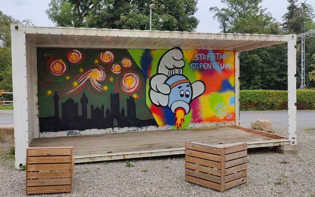 U27 Streetart Stipendium Landsberg 2024: Papierbach Kunstwerke an einem Container von Emma und Bjarne im Rahmen des U27 Streetart-Stipendiums