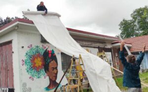 Streetart-Begegnung zwischen den Kulturen mit Lucce aus Toulouse und Erwa.One aus Landsberg. Helfer spannen eine Behelfsplane als regenschutz aus