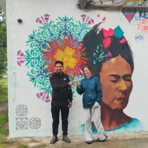 Streetart-Begegnung zwischen den Kulturen mit Lucce aus Toulouse und Erwa.One aus Landsberg. Wandgestaltung am Unser Theater Schwabhausen mit einem Portrait von Frida Kahlo und dem Schablonen-Stil der neuen Ornamente. Sprühdose und Pinsel Kombination, Beide Künstler posieren vor dem Bild und stoßen gemeinsam auf die erfolgreiche Zusammenarbeit an, interkulturelle Zusammenarbeit