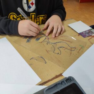 Sprüh-Workshop Urbane Kunst Methodik von ErwaOne an der Montessori-Schule von Kaufering. Ein Junge schneidet eine Schablone mit einem Skalpell