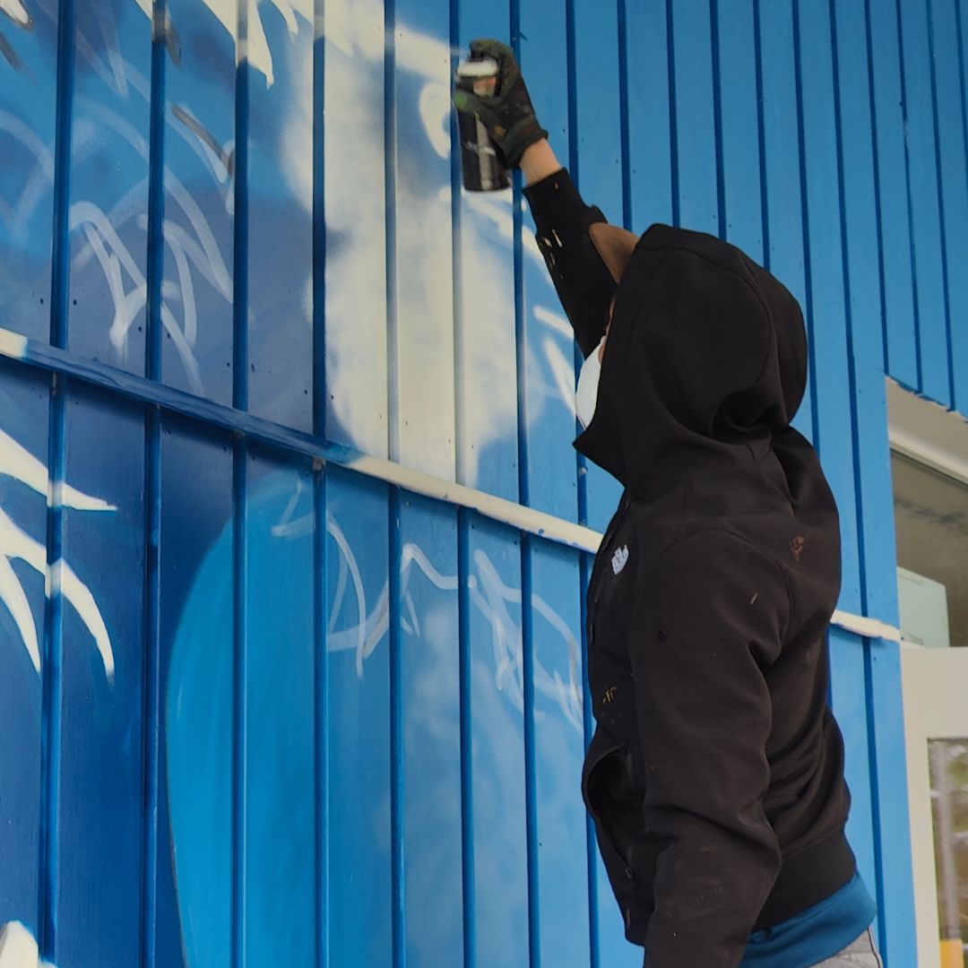 Streetart Künstler ErwaOne bei der Arbeit an einer modernen Interpretation der großen Welle vor Kanagawa von Hokusai an der Außenwand des Jugendzentrums Lechside Lounge. Urbane Kunst und Jugendarbeit