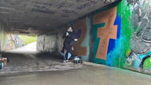 Zwei junge Frauen sprühen gemeinsam ein Graffiti an der legalen Sprühfläche von Landsberg