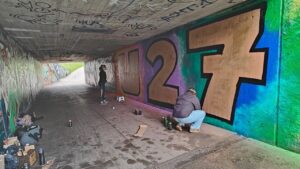 Zwei junge Frauen sprühen gemeinsam ein Graffiti an der legalen Sprühfläche von Landsberg