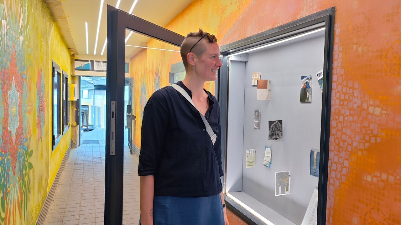 N.E.A. New Emerging Artists Ausstellung Zederpassage Landsberg mit Künstlerin Katharina Stumm vor einem Schaukasten und ihrer Postkarten-Installation