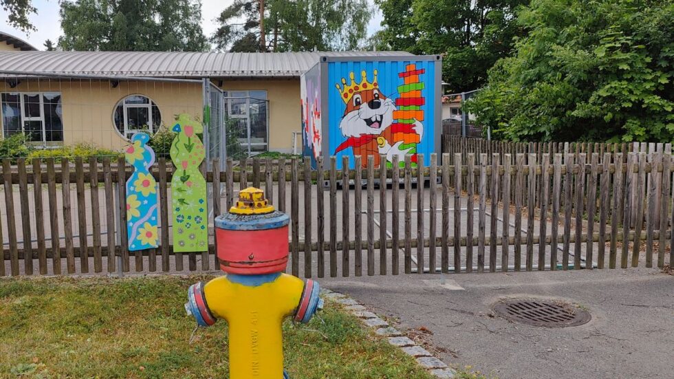 Streetart Gestaltung einer Container-Fläche mit dem Motiv eines Biber welcher einen Turm aus Holzklötzen in der Hand hält und lächelt. Ort Kindergarten Biberburg in Scheuring bei Landsberg am Lech. Auftragsarbeit Kunst im öffentlichen Raum by Erwa.One