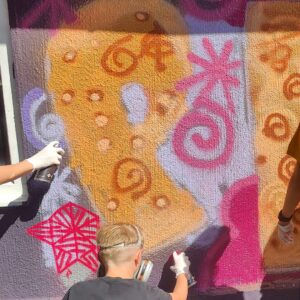 Graffiti- und Streetart Workshop mit Erwa.One in Herrsching am Ammersee. Mehrere Teilnehmer sprühen Peace an die Wand
