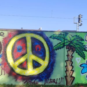Graffiti- und Streetart Workshop mit Erwa.One in Herrsching am Ammersee. Ein Peace Zeichen auf der Wand. Daneben ist eine gesprühte Palme zu sehen