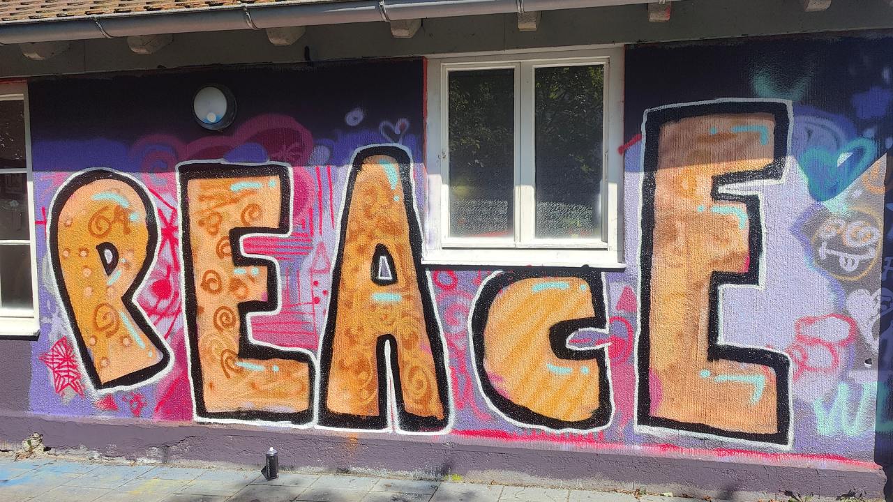 Partizipatives Graffiti aus einem Graffiti- und Streetart Workshop mit Erwa.One in Herrsching am Ammersee. Der Schriftzug Peace / Frieden steht auf einer Wand als Graffito gesprüht.