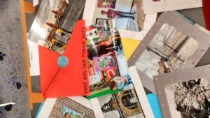 Postkarten und Fotos sowie ein roter Umschlag liegen auf einer Fläche verteilt. Solo Ausstellung des renommierten Künstlers Erwa.one