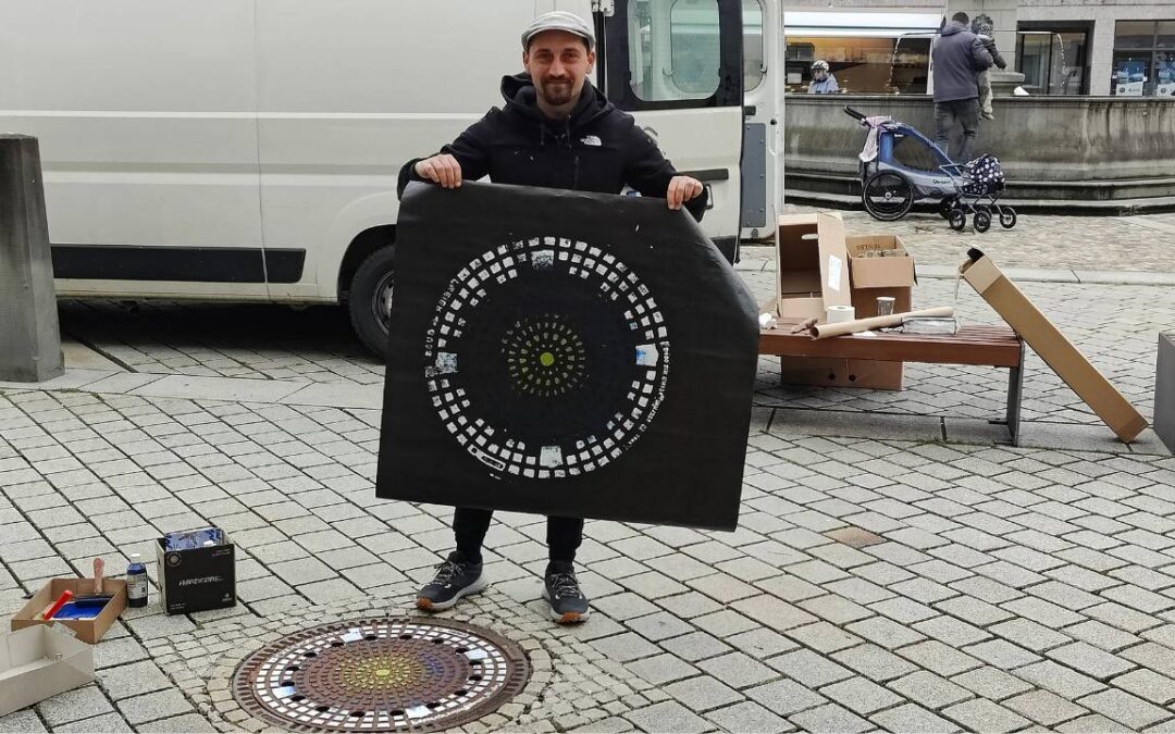 Streetart Künstler zeigt in Mindelheim einen abgedruckten Gulli-Deckel während seiner Print-the-City Intervention KulTOURtage Mindelheim Unterallgäu