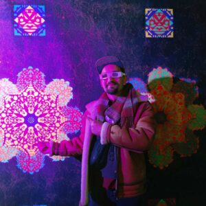 Erwa.One zeigt auf ein Ornament in seinem Klangraum in der Dillsteinerstrasse Pforzheim im Rahmen der Pforzheimer Kulturnacht. Er trägt einen Wintermantel und eine Papierbrille.