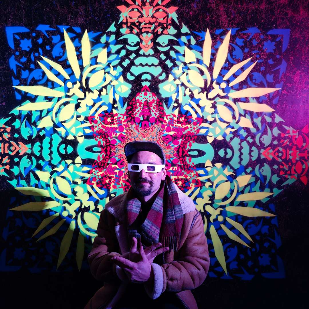 Künstler ErwaOne vor seinem Ornament des KLangraumes in Pforzheim. Er lächelt in die Kamera und trägt eine weiße Effektbrille.