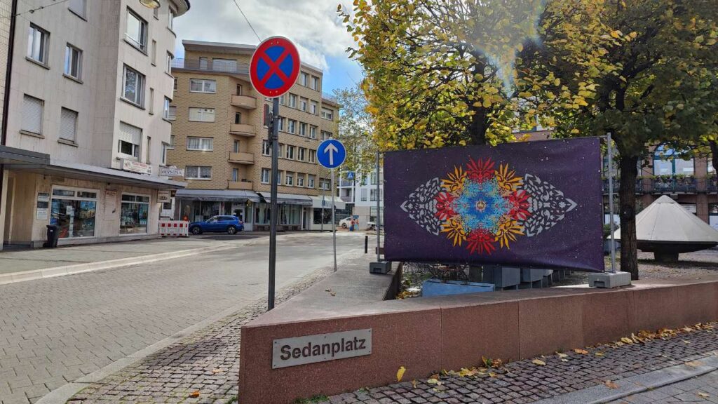 Ornament Sedanplatz auf einem Bauzaun aufgespanntes, bunt mit Schablonen motiven besprühtes Kunstwerk. Kunst im Öffentlichen Raum in Pforzheim