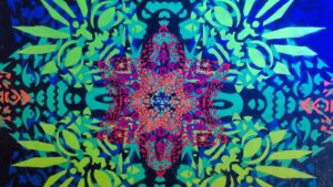 Detail eines Ornamentes im Klangraum von Erwa.One in Pforzheim. Es zeigt einen Stern, welcher von maskenähnlichen Ornamenten umgeben ist und im Schwarzlicht leuchtet.