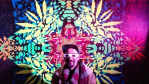 Künstler ErwaOne vor seiner Klangrauminstallation in Pforzheim. Er trägt eine Effekt-Brille und lächelt in die Kamera.