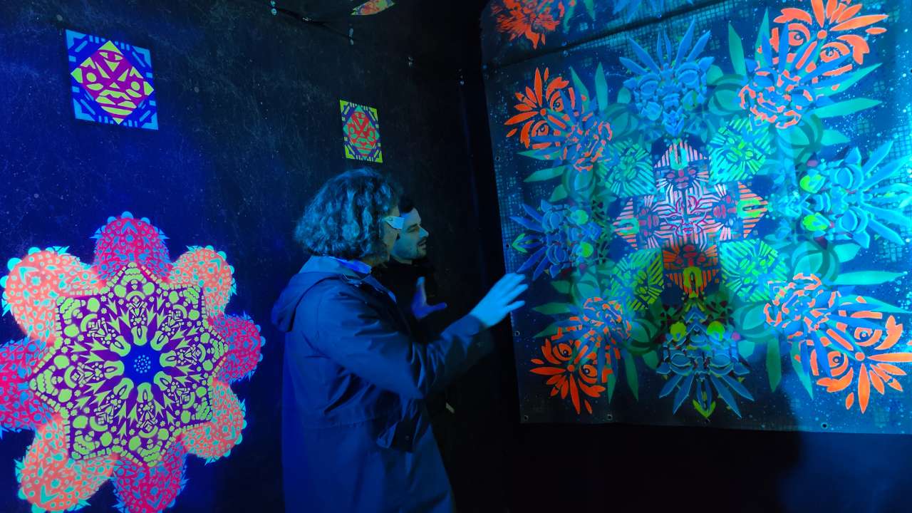 Zwei Personen unterhalten sich im gestaltten Raum von ErwaOne und zeigen auf die Elemente der Klangraum-Installation, welche den Raum inLichtwechsel verändert.