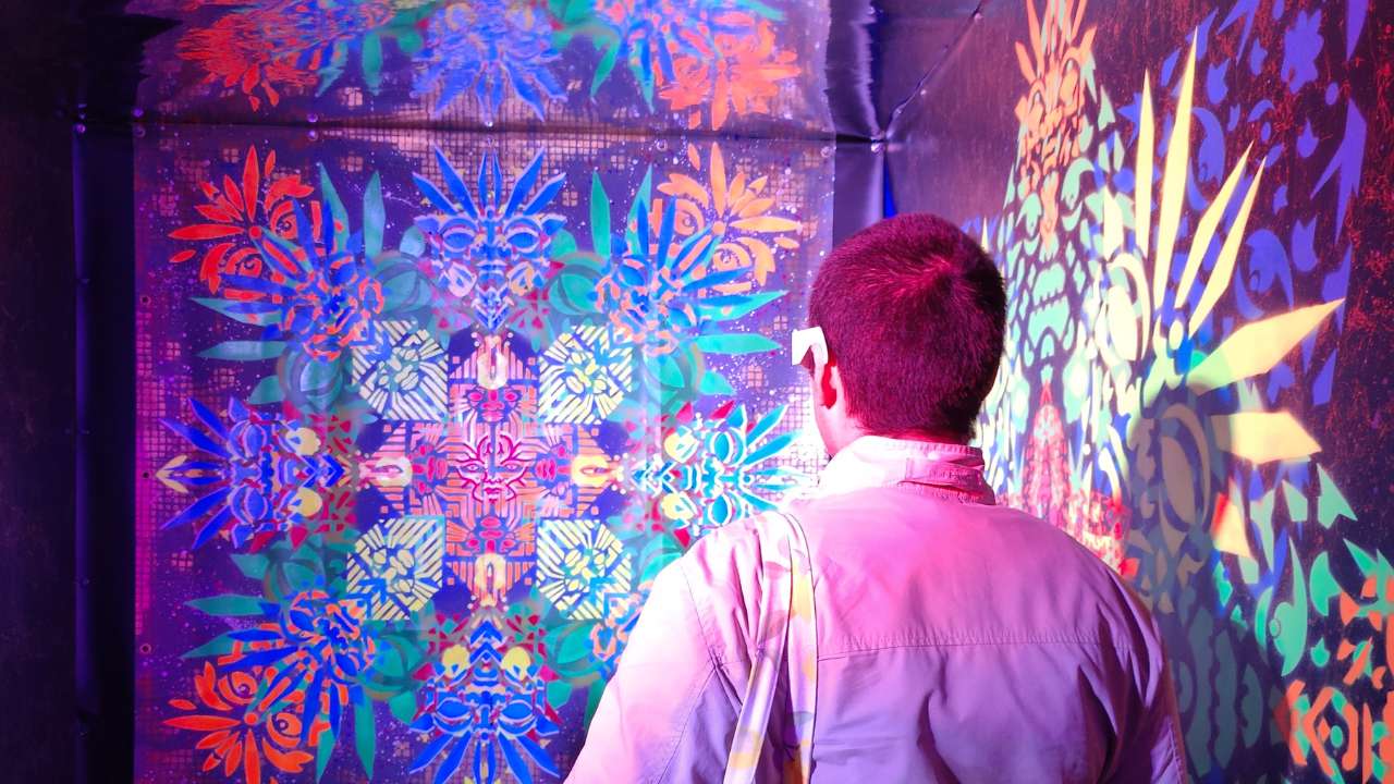 Ein Mann blickt auf die Klangraum Installation von ErwaOne im Rahmen der 6. Pforzheimer Kulturnacht. Die Motive leuchten und blinken invverschiedenen Farben. Der Mann trägt eine Effekt-Brille.vImmersive Kunstinstallation