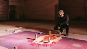 Streetart Künstler Erwa.One bei der Vorbereitung eines riesigen Kunstwerkes mit seinem Designkonzept Neue Ornamente für die Pforzheimer Kulturnacht. Er sitzt in der Hoch vor seinem Kunstwerk welches in Arbeit ist. Er trägt eine Sprühmaske