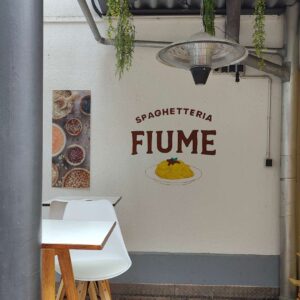 B2B Auftragsgestaltung für einen Gastronomiebetrieb Fiume in Landsberg am Lech. Ausschnitt auf Terrasse Schriftzug Spaghetteria Fiume in Siena-Braun darunter Motiv spaghetti gemalt mit Pinsel