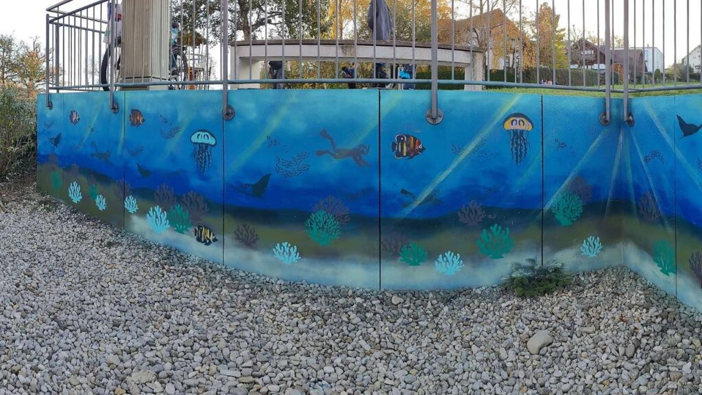Kunstprojekt offene Jugendarbeit in Pöcking am Starnberger See. Thema des Streetart-Projektes "Unterwasserwelt" auf einer Betonmauer am Schwimmbad von Pöcking. Fertiges Wandbild Unterwasserwelt. Korallen, Fische, Quallen, Taucher und Rochen sind auf dem Bild zusehen.