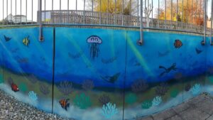 Kunstprojekt offene Jugendarbeit in Pöcking am Starnberger See. Thema des Streetart-Projektes "Unterwasserwelt" auf einer Betonmauer am Schwimmbad von Pöcking. Fertiges Wandbild Unterwasserwelt. Korallen, Quallen, Fische, Rochen, Taucher